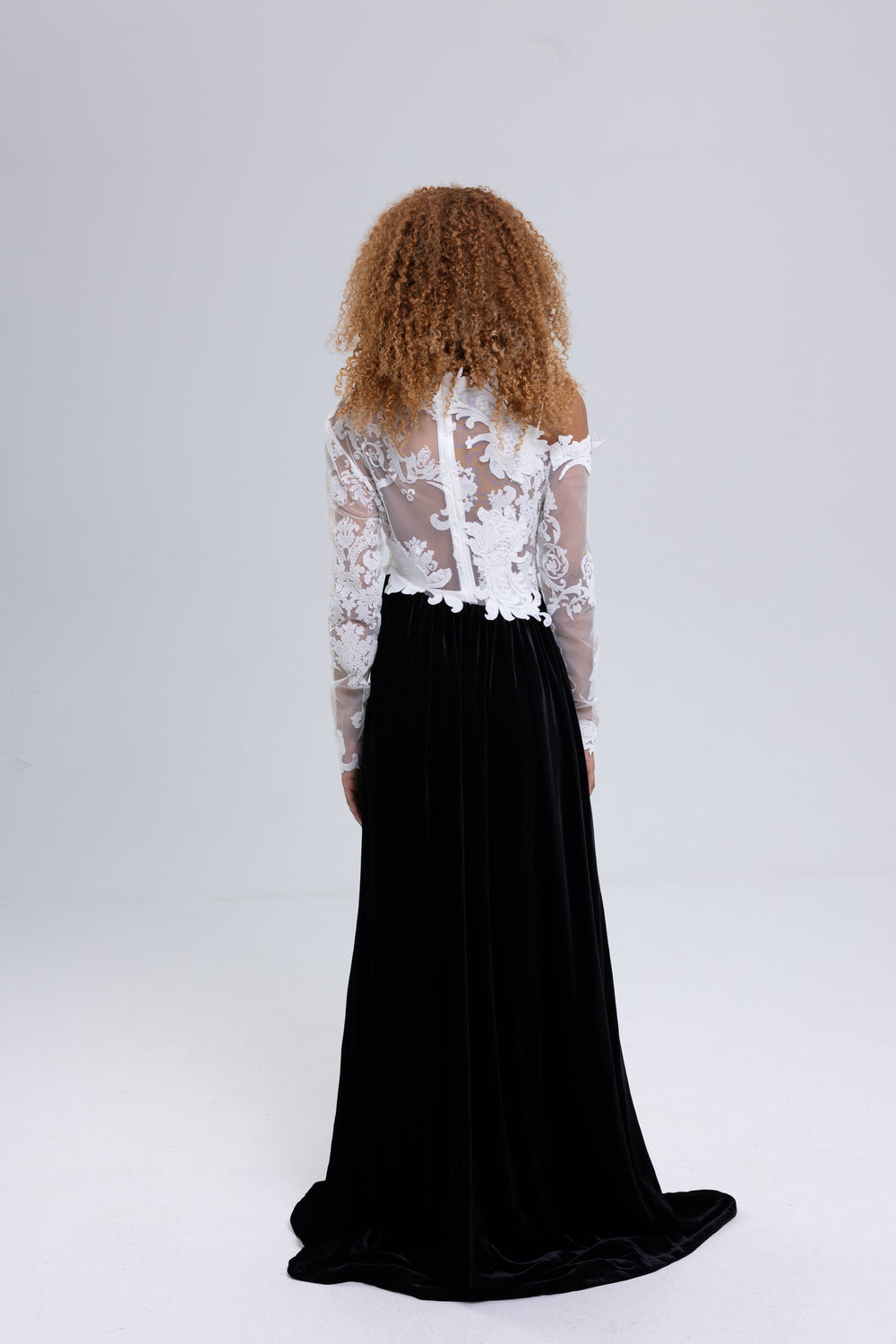 Back view of a black velvet evening gown with white lace top and train - Baleni