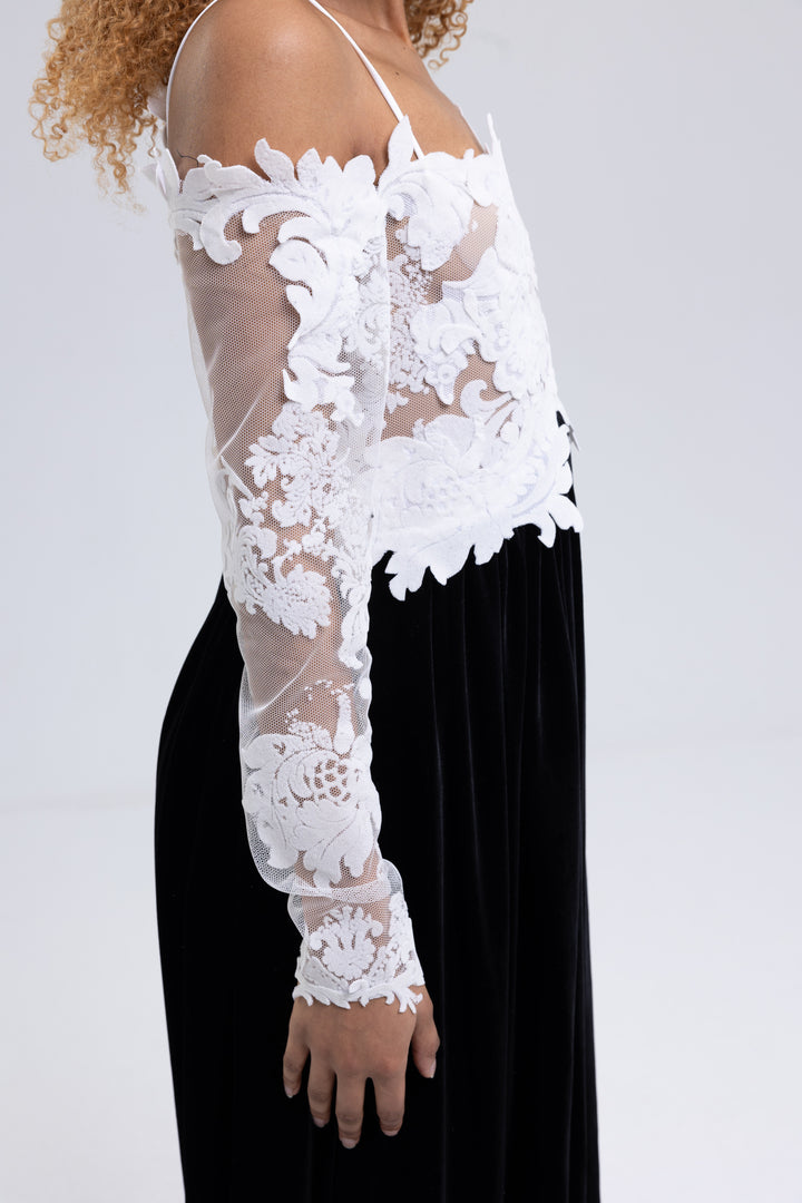 Side view of an off-shoulder lace evening gown with long sheer lace sleeves and black velvet skirt - Baleni