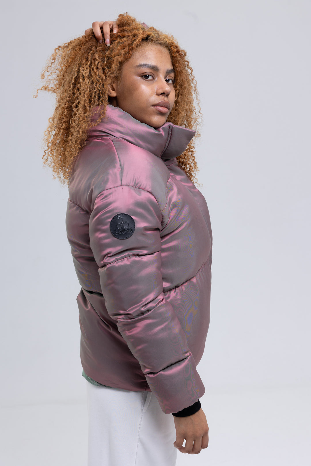 Side view of a pink puffer jacket with high funnel neck and leather logo patch on the sleeve - Baleni