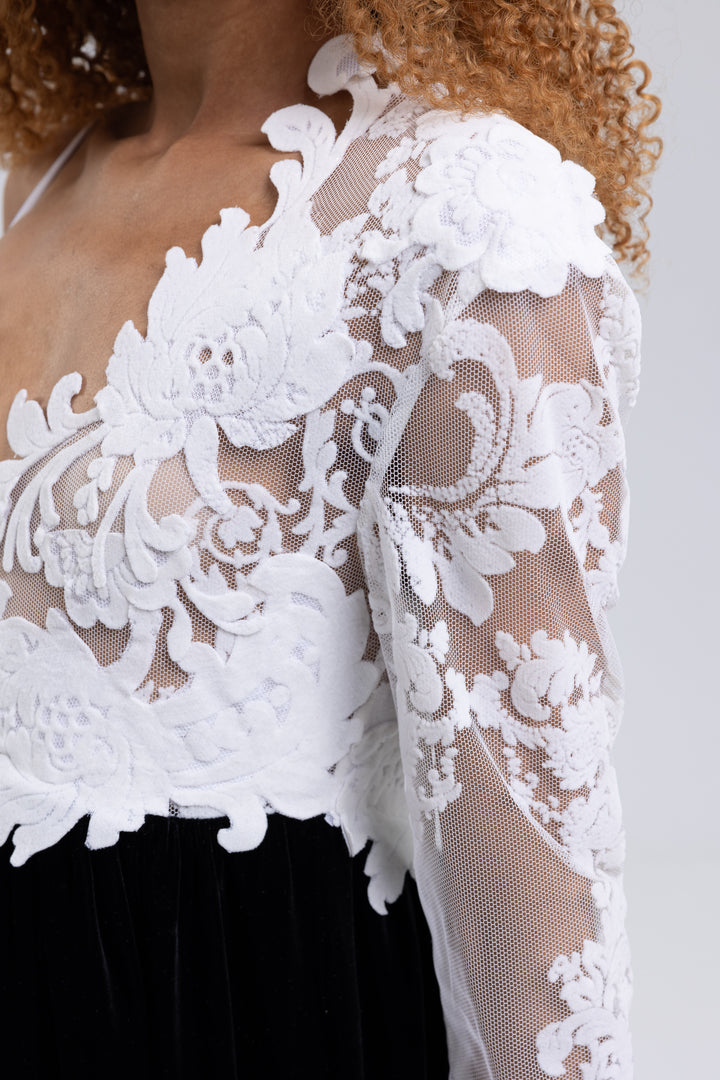 Close-up of the white floral lace bodice and sheer sleeve of a black and white evening gown - Baleni